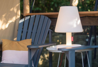 Zona relax esterna con due sedie, cuscini e lampada presso la tenda Safari Lodge al Camping Delle Rose, Italia.