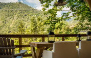 Vista desde la tienda safari Base Lodge en Camping Delle Rose, Italia, con sillas, mesa y paisaje montañoso.