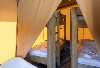 Vista interior de la tienda safari Base Lodge en Camping Delle Rose, Italia, con dos literas de madera.