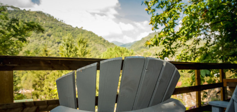 Vista desde la tienda safari Base Lodge en Camping Delle Rose, Italia, con colinas y silla de madera.