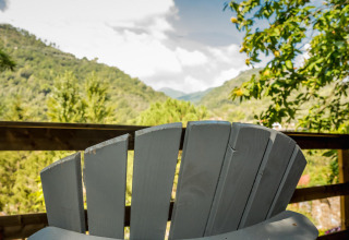 Vista desde la tienda safari Base Lodge en Camping Delle Rose, Italia, con colinas y silla de madera.