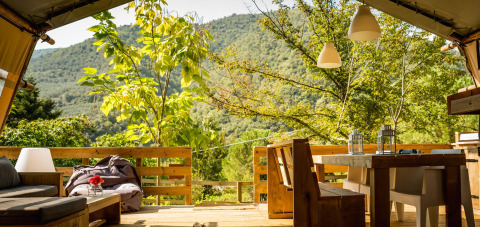 View from Desert Lodge safari tent at Camping Delle Rose in Italy, featuring a wooden deck and scenic mountains.
