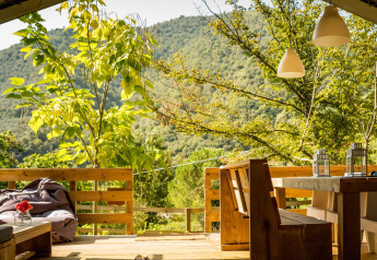 Zicht vanuit de Desert Lodge safaritent bij Camping Delle Rose in Italië, met houten terras en natuur.