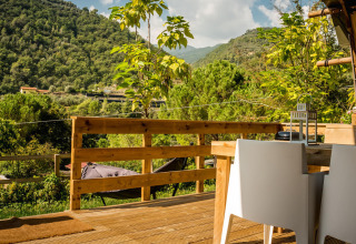 View from a Desert Lodge safari tent at Camping Delle Rose, Italy, with wooden deck and lush mountain scenery.