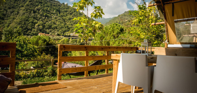 Uitzicht vanaf een Desert Lodge safaritent op Camping Delle Rose in Italië met houten terras en groene bergen.