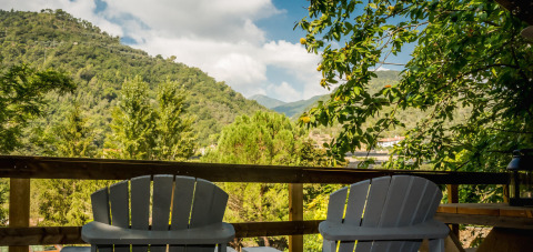 Two chairs on a terrace overlooking lush green hills and trees at Camping Delle Rose, Italy.