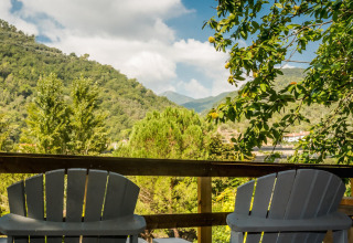 Twee stoelen op een terras met uitzicht op groene heuvels en bomen bij Camping Delle Rose, Italië.