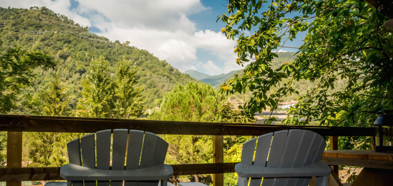 Dos sillas en una terraza con vistas a colinas verdes y árboles en Camping Delle Rose, Italia.