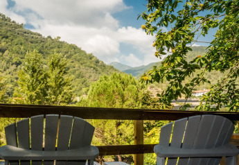Two chairs on a terrace overlooking lush green hills and trees at Camping Delle Rose, Italy.