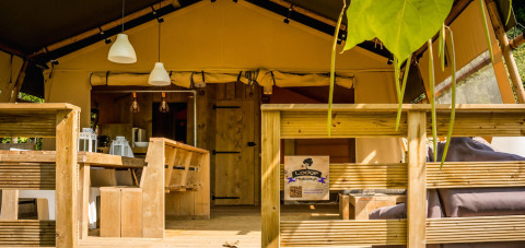 Desert Lodge safari tent at Camping Delle Rose in Italy, featuring a wooden terrace and outdoor seating area.
