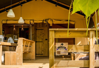 Tenda safari Desert Lodge al Camping Delle Rose in Italia con terrazza in legno e area salotto esterna.