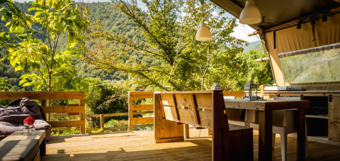 Outdoor dining area at Desert Lodge safari tent at Camping Delle Rose, overlooking lush green mountains in Italy.