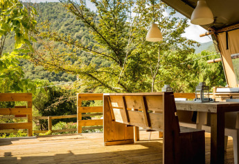 Outdoor dining area at Desert Lodge safari tent at Camping Delle Rose, overlooking lush green mountains in Italy.