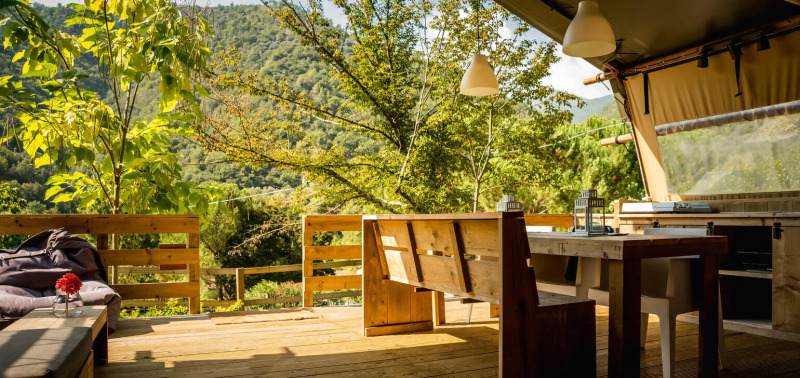 Buiten eethoek van safari tent Desert Lodge bij Camping Delle Rose, met uitzicht op groene bergen in Italië.