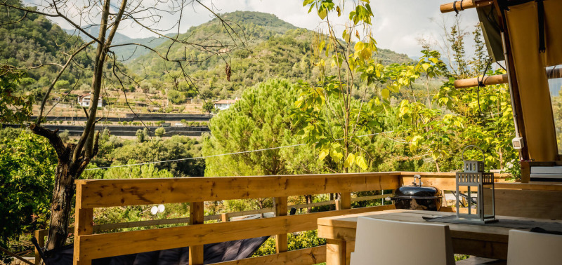 Vista desde la tienda safari Desert Lodge en Camping Delle Rose, Italia, con montañas y vegetación.