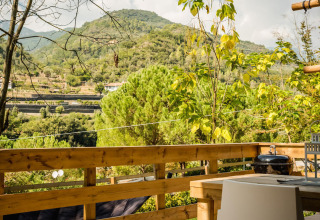 Vista desde la tienda safari Desert Lodge en Camping Delle Rose, Italia, con montañas y vegetación.