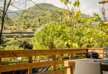 View from the Desert Lodge safari tent at Camping Delle Rose, Italy, overlooking mountains and greenery.