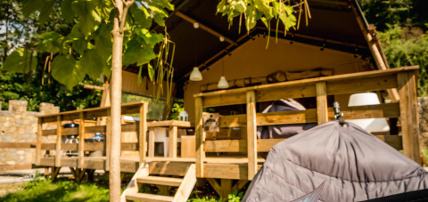 Safari tent Desert Lodge at Camping Delle Rose, Italy, with wooden terrace surrounded by green nature.