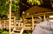Tenda safari Desert Lodge al Camping Delle Rose in Italia, terrazza in legno immersa nella natura soleggiata.
