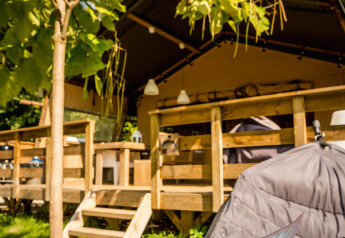 Safari tent Desert Lodge at Camping Delle Rose, Italy, with wooden terrace surrounded by green nature.