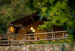 Desert Lodge safari tent at Camping Delle Rose in Italy, surrounded by lush greenery and a wooden terrace.
