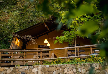 Desert Lodge safari tent at Camping Delle Rose in Italy, surrounded by lush greenery and a wooden terrace.