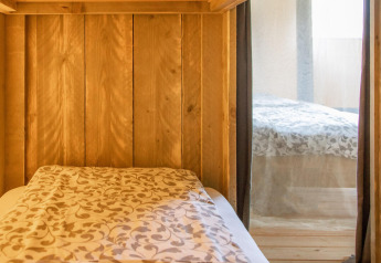 Vista interior de una tienda safari Wood Lodge con camas cómodas en Camping Delle Rose en Italia.