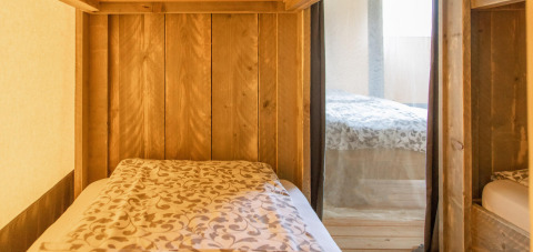 Vista interior de una tienda safari Wood Lodge con camas cómodas en Camping Delle Rose en Italia.