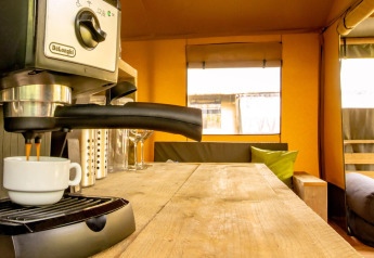 Cafetera preparando espresso en el interior de madera de la tienda safari Wood Lodge en Camping Delle Rose, Italia.
