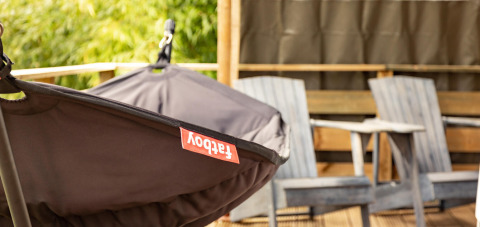 Close-up van een Fatboy hangmat en twee houten stoelen op het terras van de Wood Lodge tent, Camping Delle Rose.