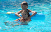 Two smiling children playing together in the pool at Camping Delle Rose holiday park in Liguria, Italy.