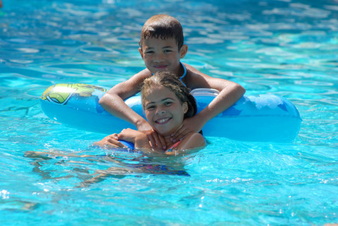 Deux enfants souriants jouent ensemble dans la piscine du Camping Delle Rose en Ligurie, Italie.