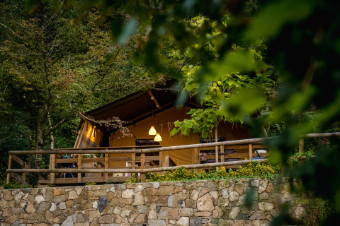 Knusse glampingtent bij Camping Delle Rose in Ligurië, Italië, omgeven door groen en bosrijke natuur.