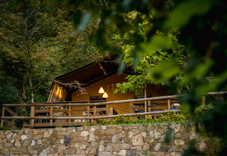 A cozy glamping tent at Camping Delle Rose in Liguria, Italy, surrounded by lush forest and greenery.