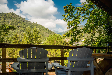 Zwei Stühle auf einer Holzterrasse mit Blick auf grüne Hügel bei Isolabona in Ligurien, Italien.
