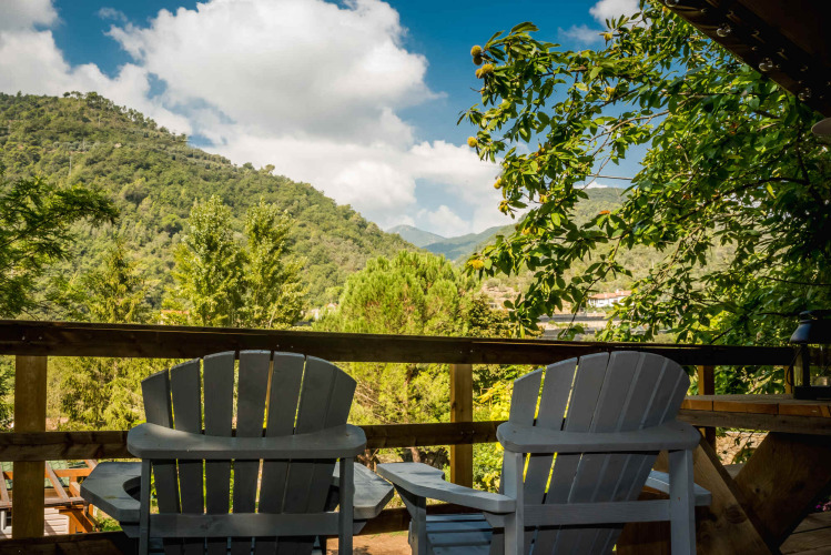 Twee stoelen op een houten terras met uitzicht op groene heuvels nabij Isolabona, Ligurië, Italië.