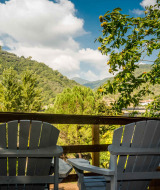 Two chairs on a wooden terrace overlooking lush green hills near Isolabona, Liguria, Italy.