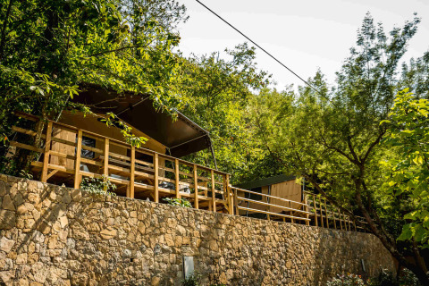 Cabañas con terraza rodeadas de vegetación y árboles en Camping Delle Rose, Liguria, Italia.