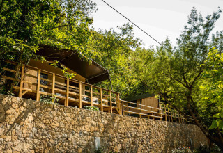 Terrassehytter omgivet af træer og grønne omgivelser på Camping Delle Rose i Ligurien, Italien.