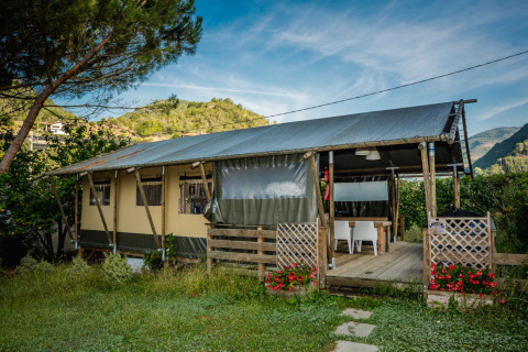 Tienda safari en Camping Delle Rose, Liguria, Italia, rodeada de naturaleza y montañas, con terraza de madera.