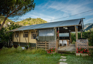 Safaritent op Camping Delle Rose in Ligurië, Italië, omgeven door bergen en bloemen in een groene omgeving.