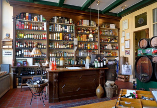 Interior view of the cozy bar at Camping Vrijhaven Heeg, with shelves of bottles and vintage barrels.