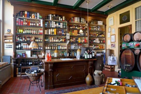 Interno del bar accogliente di Camping Vrijhaven Heeg, con scaffali pieni di bottiglie e botti vintage.