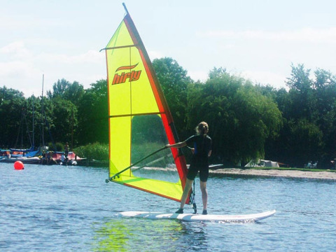 Persona che fa windsurf al Campeggio Vrijhaven Heeg, villaggio vacanze in Frisia, Paesi Bassi, con vela verde.