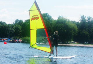 Persona che fa windsurf al Campeggio Vrijhaven Heeg, villaggio vacanze in Frisia, Paesi Bassi, con vela verde.