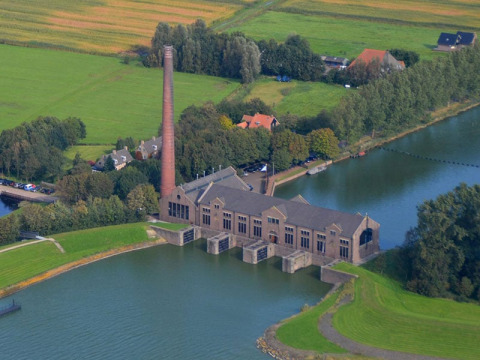 Vista aerea di Camping Vrijhaven Heeg, parco vacanze in Frisia, Paesi Bassi, accanto all'acqua e ai campi verdi.