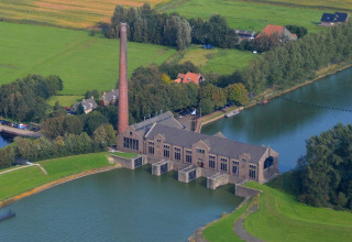 Vista aerea di Camping Vrijhaven Heeg, parco vacanze in Frisia, Paesi Bassi, accanto all'acqua e ai campi verdi.