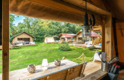 Vista desde dentro de una tienda Safari, Cozy Lodge + sanitario, con otras tiendas y césped verde afuera.