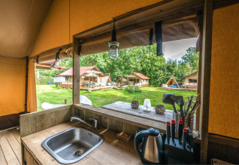 Vista desde la cocina del safari tent Cozy Lodge con baño, mostrando otras tiendas en el césped.
