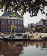 Photo d’un port dans un parc de vacances avec glamping, bateaux amarrés devant des bâtiments classiques.